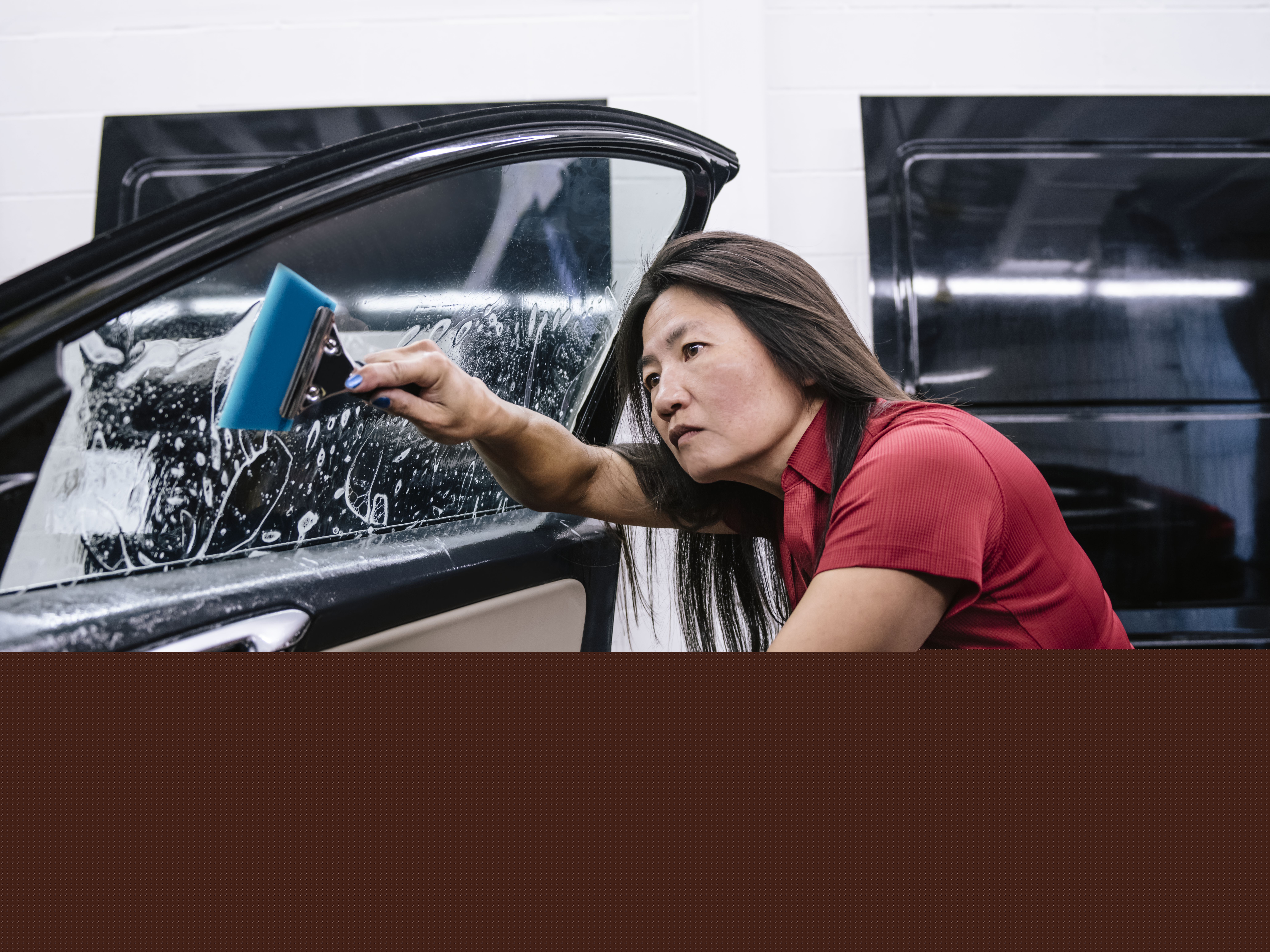 Woman applying 3M film onto a car window